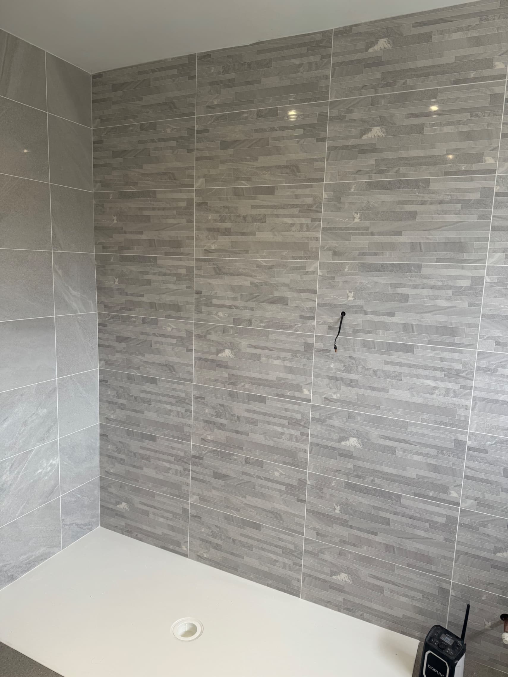 We've just finished grouting the walls with white grout to complement the grey tiles beautifully. Next we'll be decorating the space and then installing the bathroom furniture to complete the job.