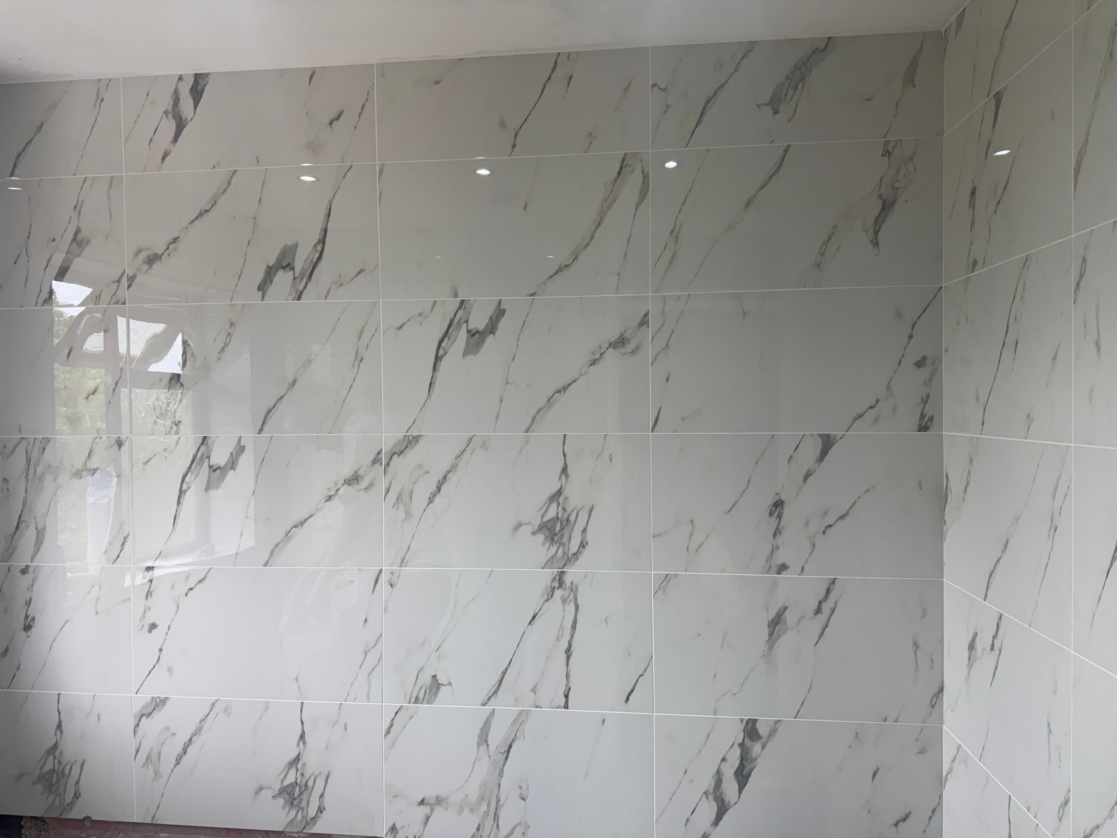 We've laid and fully grouted these beautiful marble-effect tiles, which are looking bright and fresh. Next, we're ready to install the bathroom furniture to complete the space.